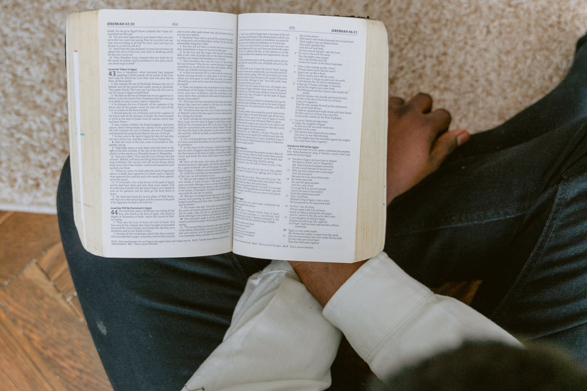 person in white long sleeve shirt and blue denim jeans reading bible