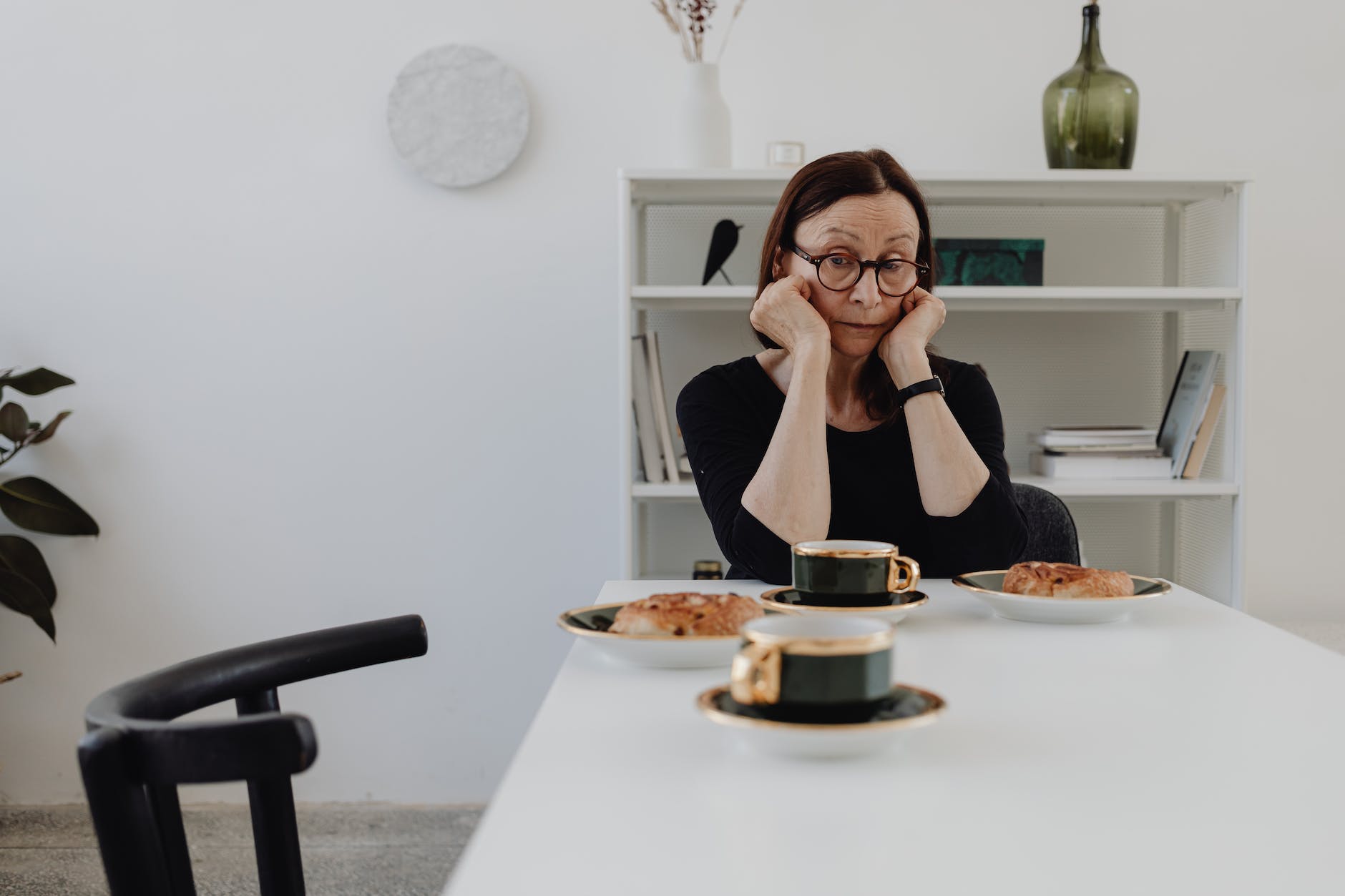 an elderly woman wearing eyeglasses while looking at the table