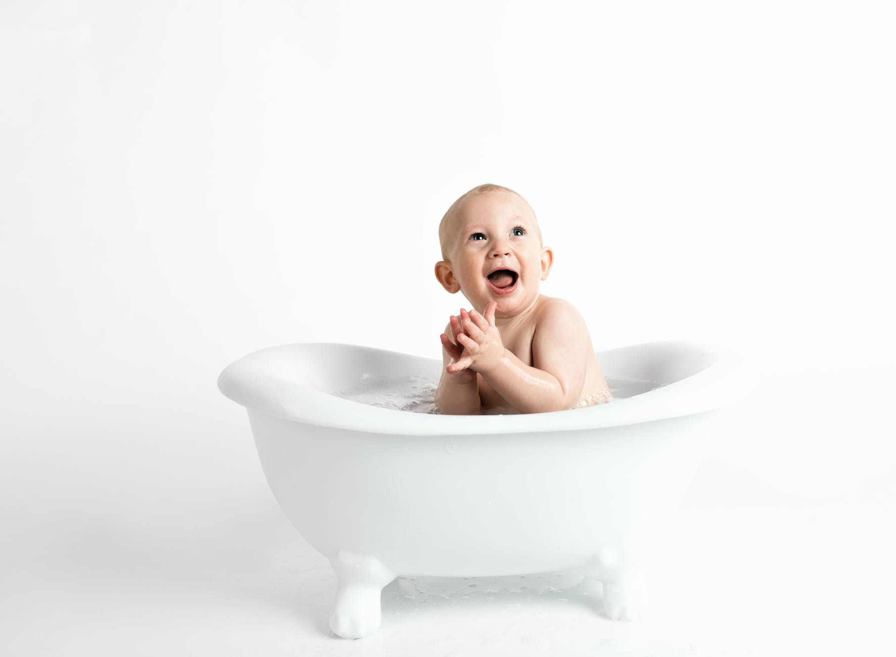 baby inside white bathtub with water